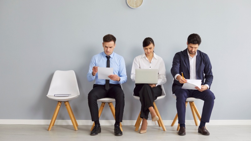 Gruppo di uomini e donne seduti in attesa di lavoro